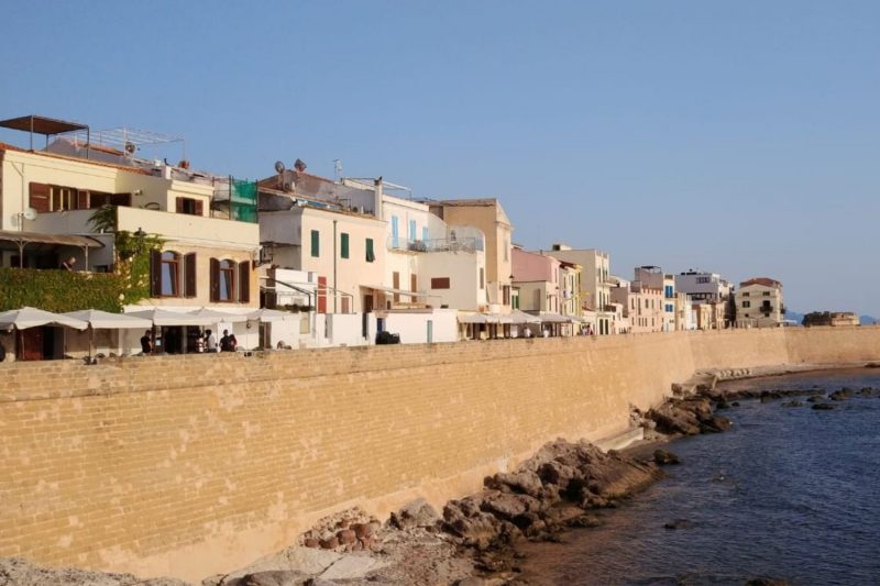 Mura sul mare di Alghero con bastioni e case affacciate sull’acqua nel centro storico