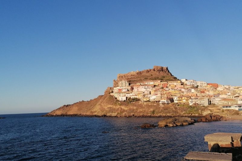 Castelsardo visto dal mare con il borgo arroccato e il castello dei Doria al tramonto