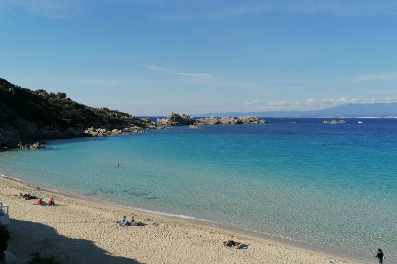 Spiaggia di Rena Bianca a Santa Teresa Gallura con acqua limpida e scogliere di Bonifacio all’orizzonte